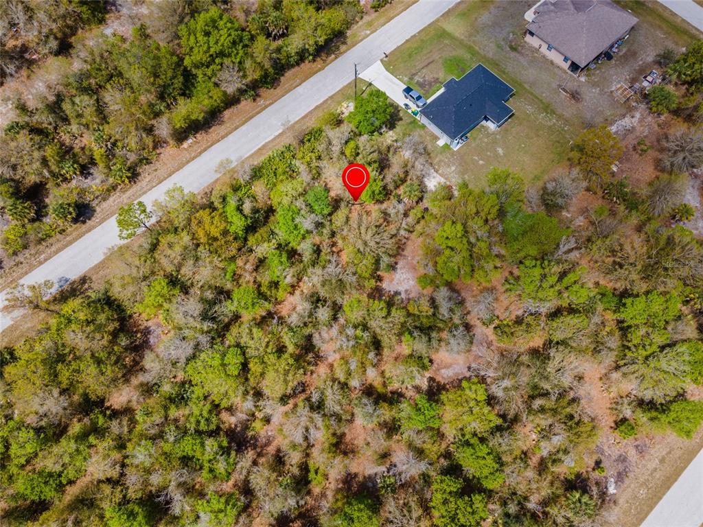 An aerial view shows a wooded, undeveloped residential lot marked with a red location pin — 7084 LIPPMAN ROAD, PORT CHARLOTTE, FL
