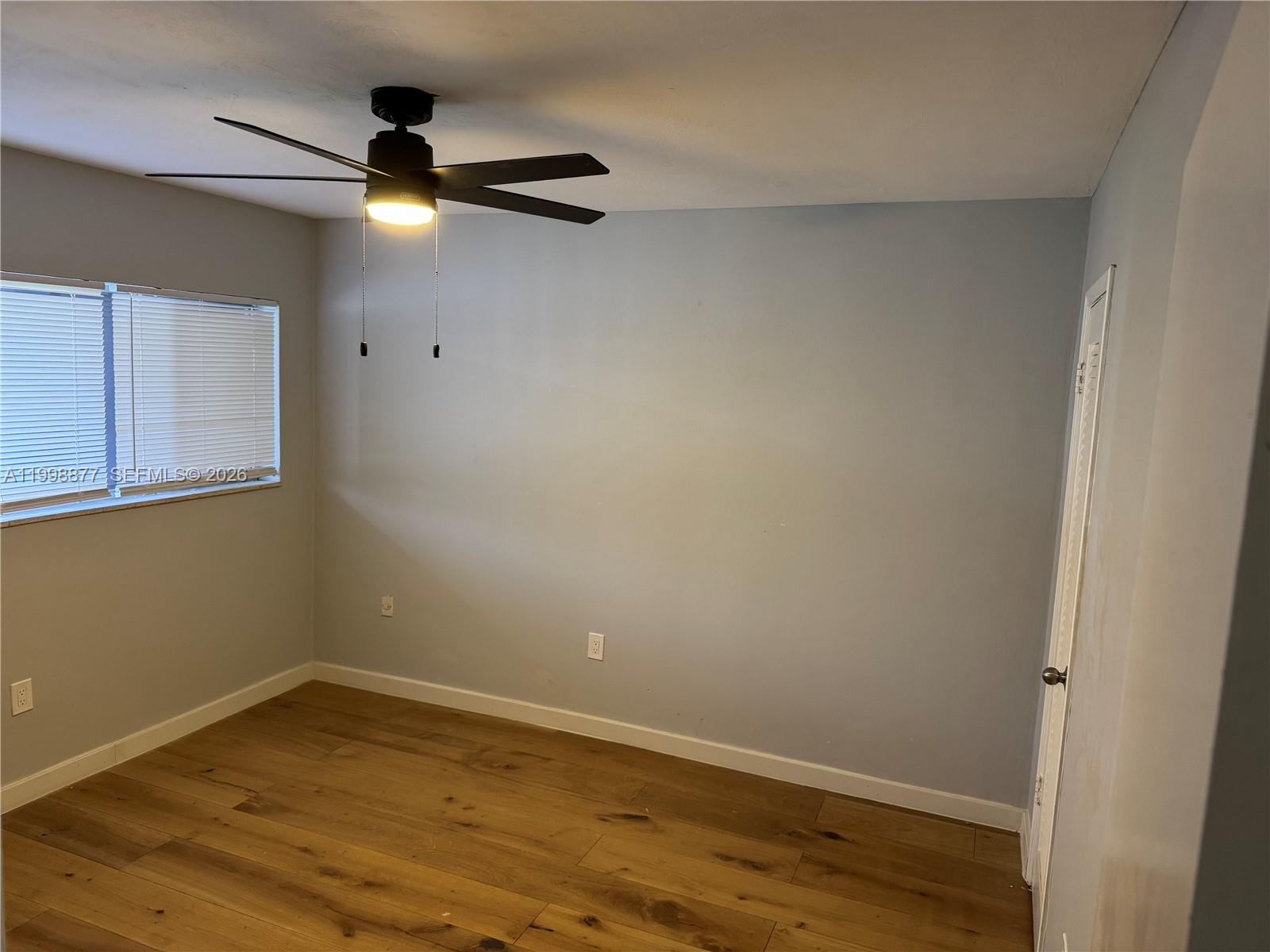 An empty room features light gray walls, wood-look flooring, a ceiling fan, and a window — 6720 Arbor Dr # 207, Miramar FL 33023, MIRAMAR, FL