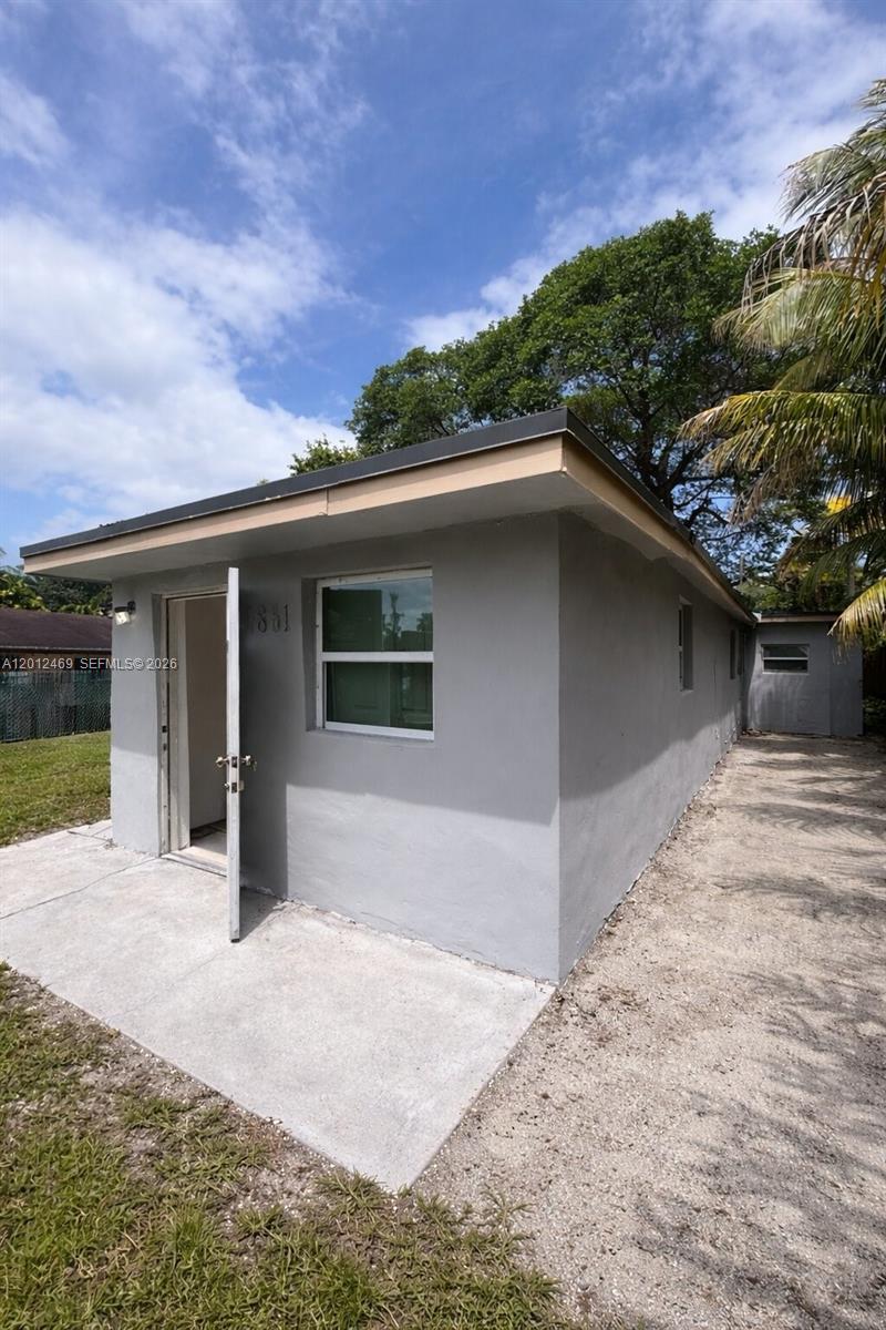 A gravel side yard runs between a gray house and a wooden fence — 1861 NW 112th St, Miami FL 33167, MIAMI, FL
