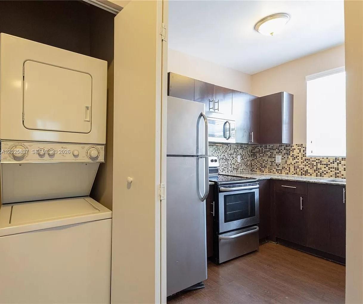 A kitchen with dark cabinets and stainless steel appliances sits next to a stacked washer-dryer — 5416 NE 1st Ct # 2, Miami FL 33137, MIAMI, FL