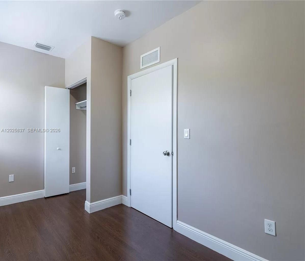 A room with dark wood flooring, beige walls, a closet, and a white door — 5416 NE 1st Ct # 2, Miami FL 33137, MIAMI, FL