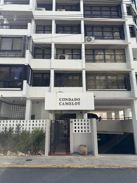 The exterior of a multi-story apartment building features a white facade and a gated entrance — 18 TAFT UNIT 2-S, SAN JUAN, PR