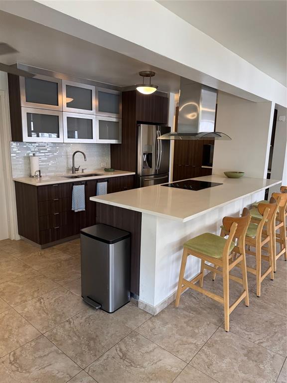 A modern kitchen features dark wood cabinets, a white island, and stainless steel appliances — 18 TAFT UNIT 2-S, SAN JUAN, PR