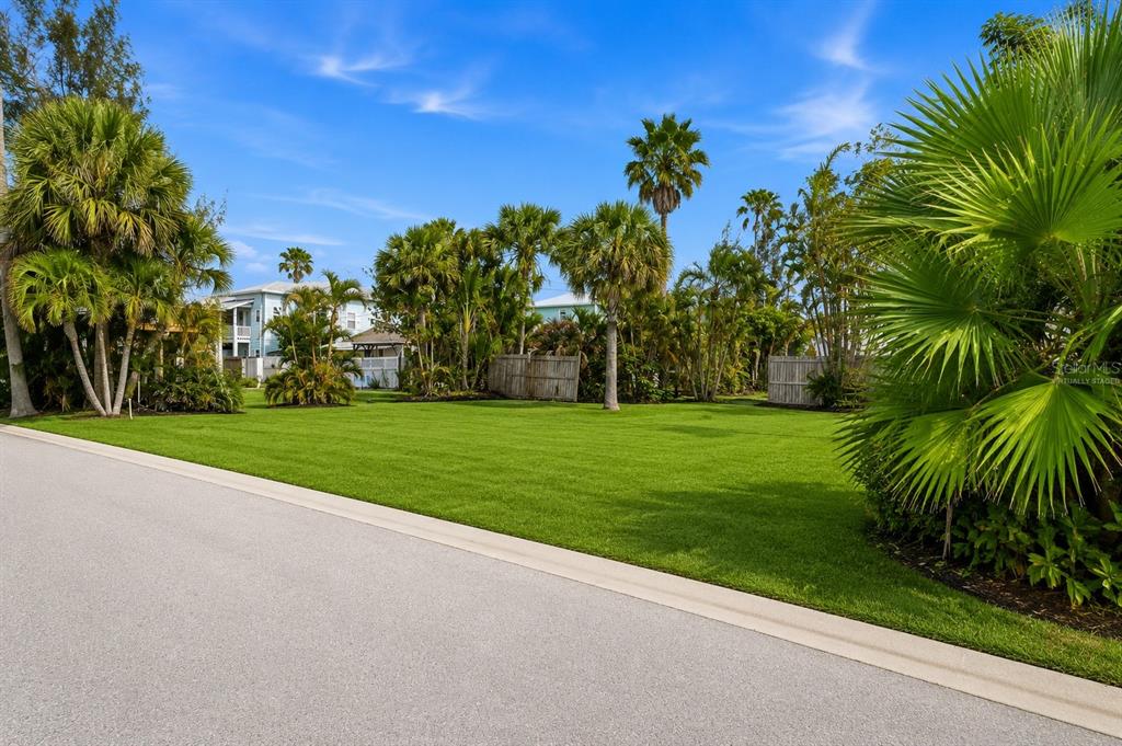 A grassy vacant lot is surrounded by palm trees and a wooden fence — 131 86TH TERRACE, ST PETERSBURG, FL