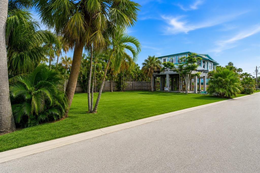 A stilt house sits behind a large green lawn surrounded by palm trees and foliage — 131 86TH TERRACE, ST PETERSBURG, FL