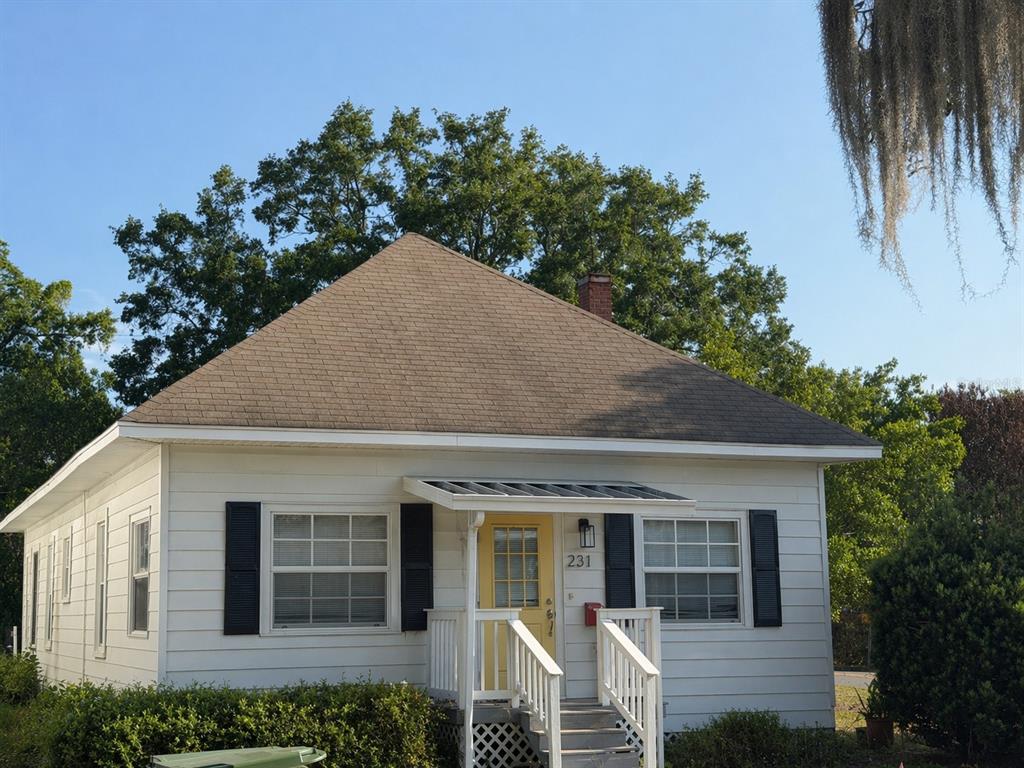 A white, single-story house with a yellow front door and a brown shingled roof — 231 AVENUE A NE, WINTER HAVEN, FL