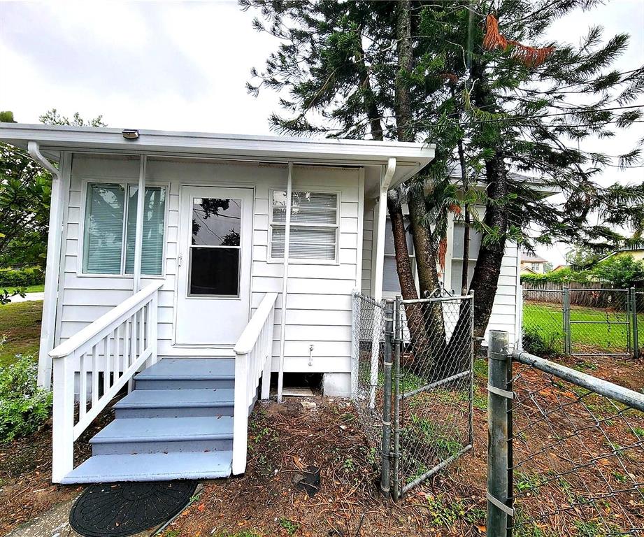 A white house exterior features a small porch with blue steps and a chain-link fence — 231 AVENUE A NE, WINTER HAVEN, FL