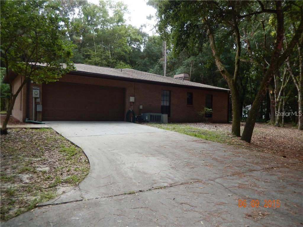 A brick house with a two-car garage and a concrete driveway surrounded by trees — 8925 QUAIL RUN DRIVE, WESLEY CHAPEL, FL