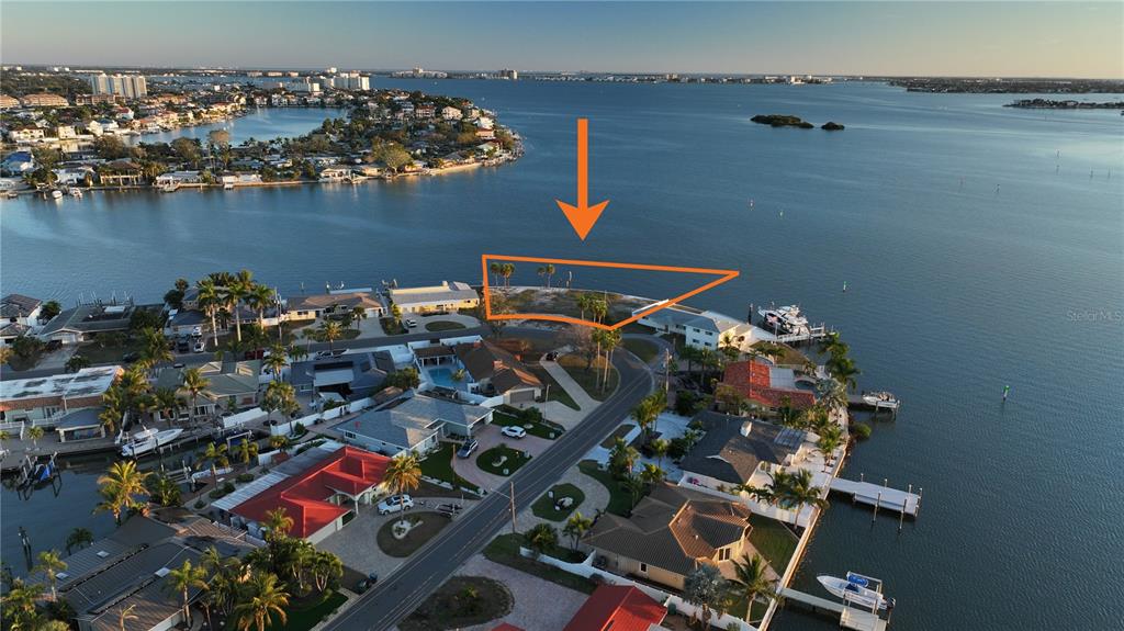 An aerial view shows a vacant, triangular waterfront lot outlined in orange near a road — 1503 SEA GULL DRIVE S, ST PETERSBURG, FL