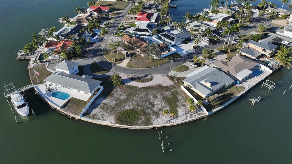An aerial view shows a vacant waterfront lot situated between two houses with pools — 1503 SEA GULL DRIVE S, ST PETERSBURG, FL
