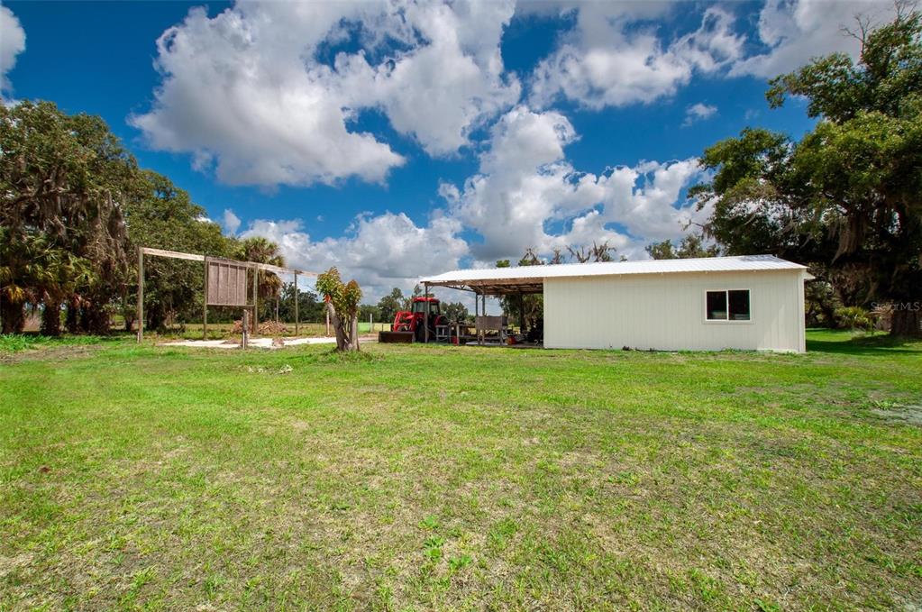 A white metal shed with an attached carport sits on a grassy rural lot — 1635 SW RODGERS AVENUE, ARCADIA, FL