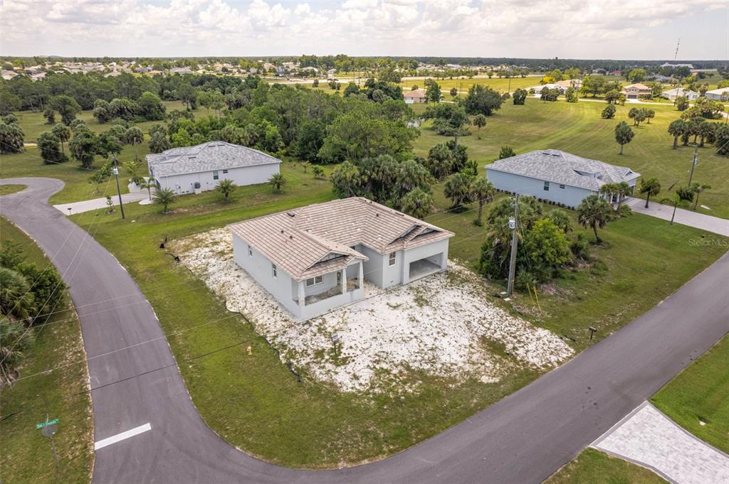 An aerial view shows a newly constructed single-story house on a corner lot with landscaping — 16265 SAN EDMUNDO ROAD, PUNTA GORDA, FL