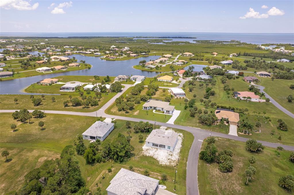 An aerial view shows a residential neighborhood with houses, green lawns, and a nearby bay — 16265 SAN EDMUNDO ROAD, PUNTA GORDA, FL