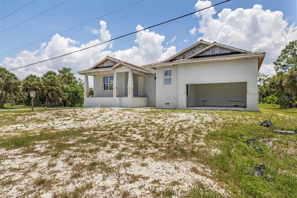 A newly constructed single-story house with an open garage and unfinished landscaping — 16265 SAN EDMUNDO ROAD, PUNTA GORDA, FL