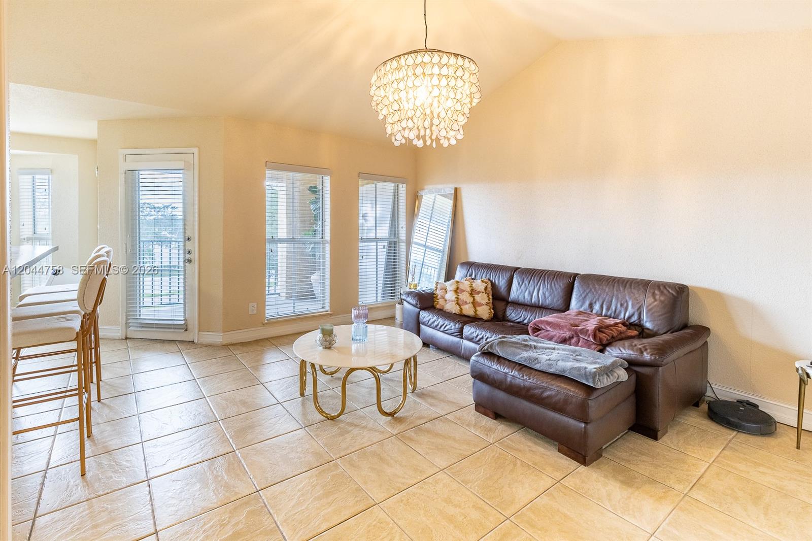 A living room features a brown leather sofa, a round coffee table, and tile flooring — CORAL SPRINGS, FL