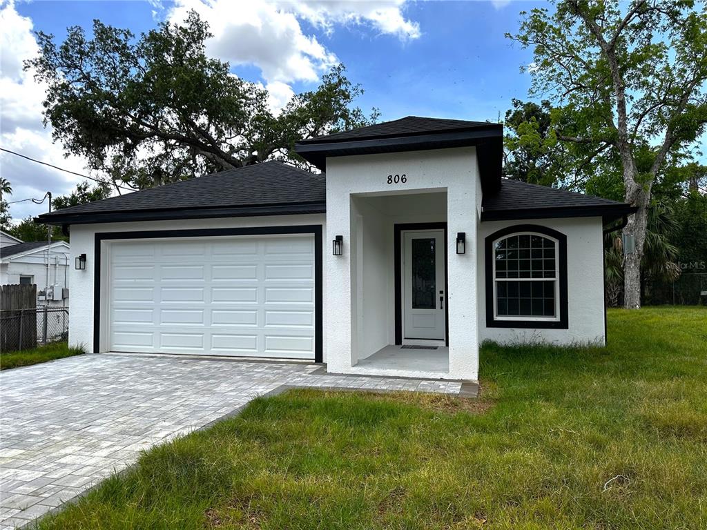 A white single-story house with a black roof, garage, and a paved driveway — 806 W LOWRY LANE, TAMPA, FL