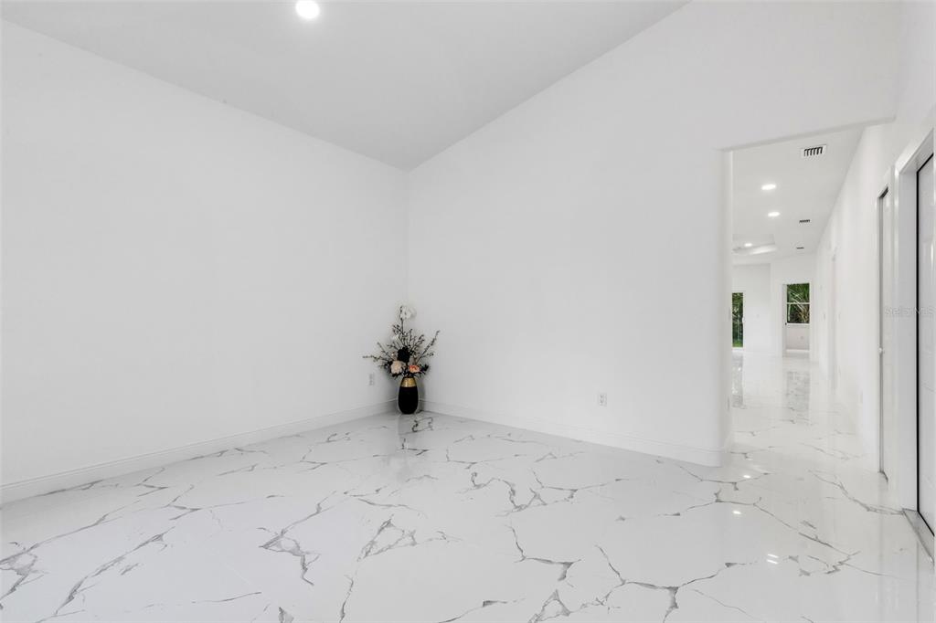 An empty room with white walls and white marble-patterned tile flooring — 806 W LOWRY LANE, TAMPA, FL