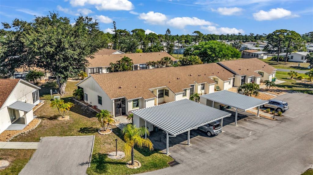 An aerial view shows a single-story residential building with a brown roof and carports — 6796 GASPARILLA PINES BOULEVARD UNIT 105, ENGLEWOOD, FL