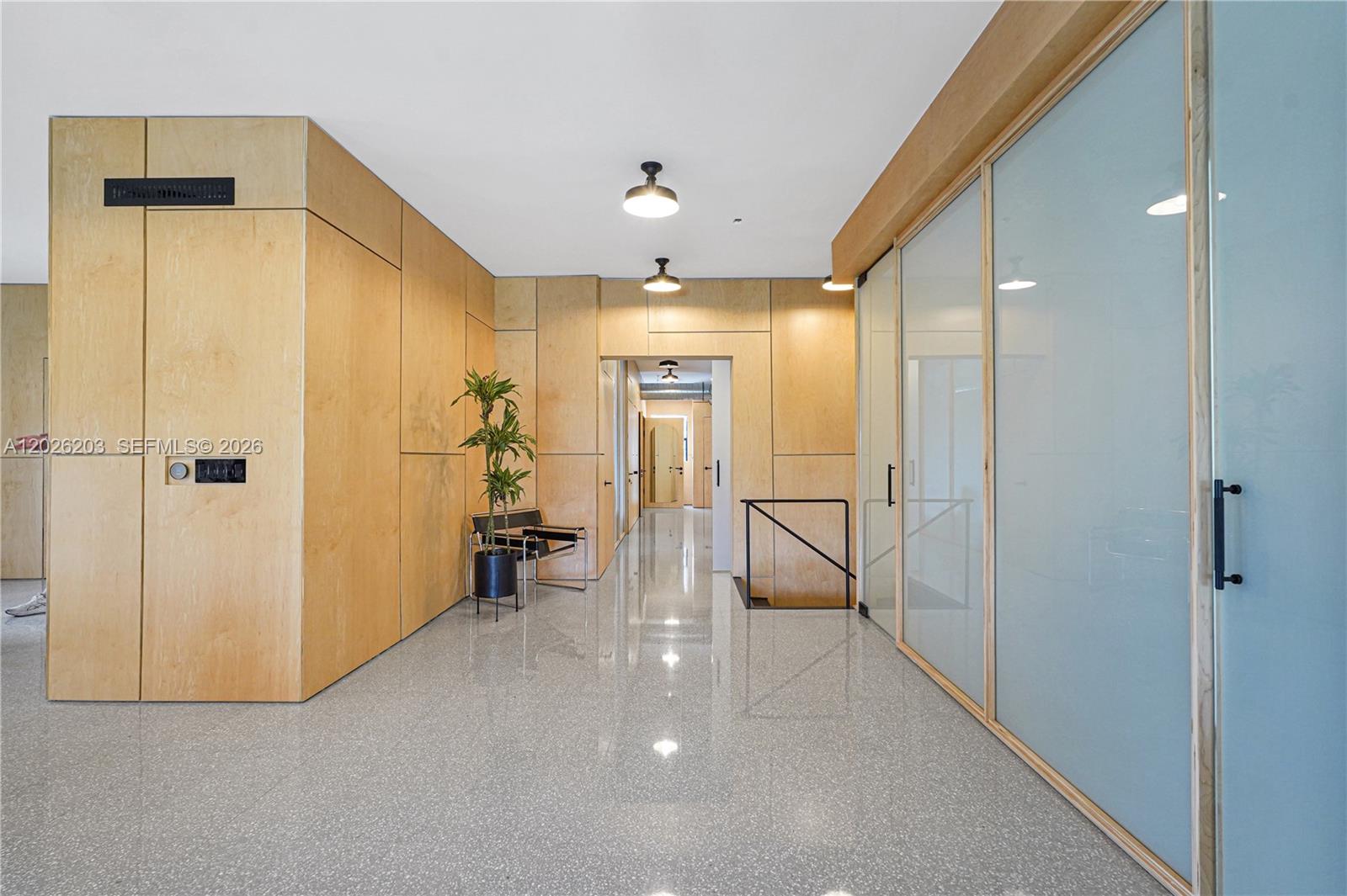 A hallway features light wood paneling, a polished speckled floor, and glass-paneled office doors — 1800 N Miami Ave, Miami FL 33136, MIAMI, FL