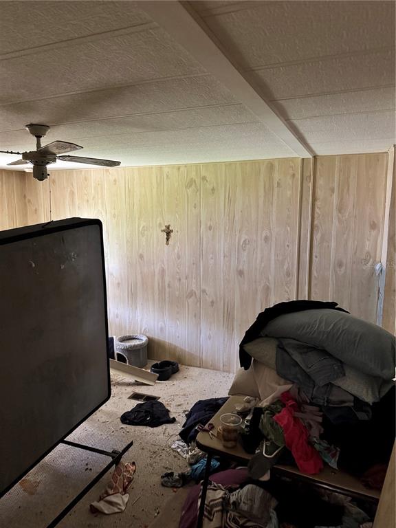 A room with wood-paneled walls, a ceiling fan, and scattered clutter on the floor — 14251 RIALTO AVENUE, BROOKSVILLE, FL