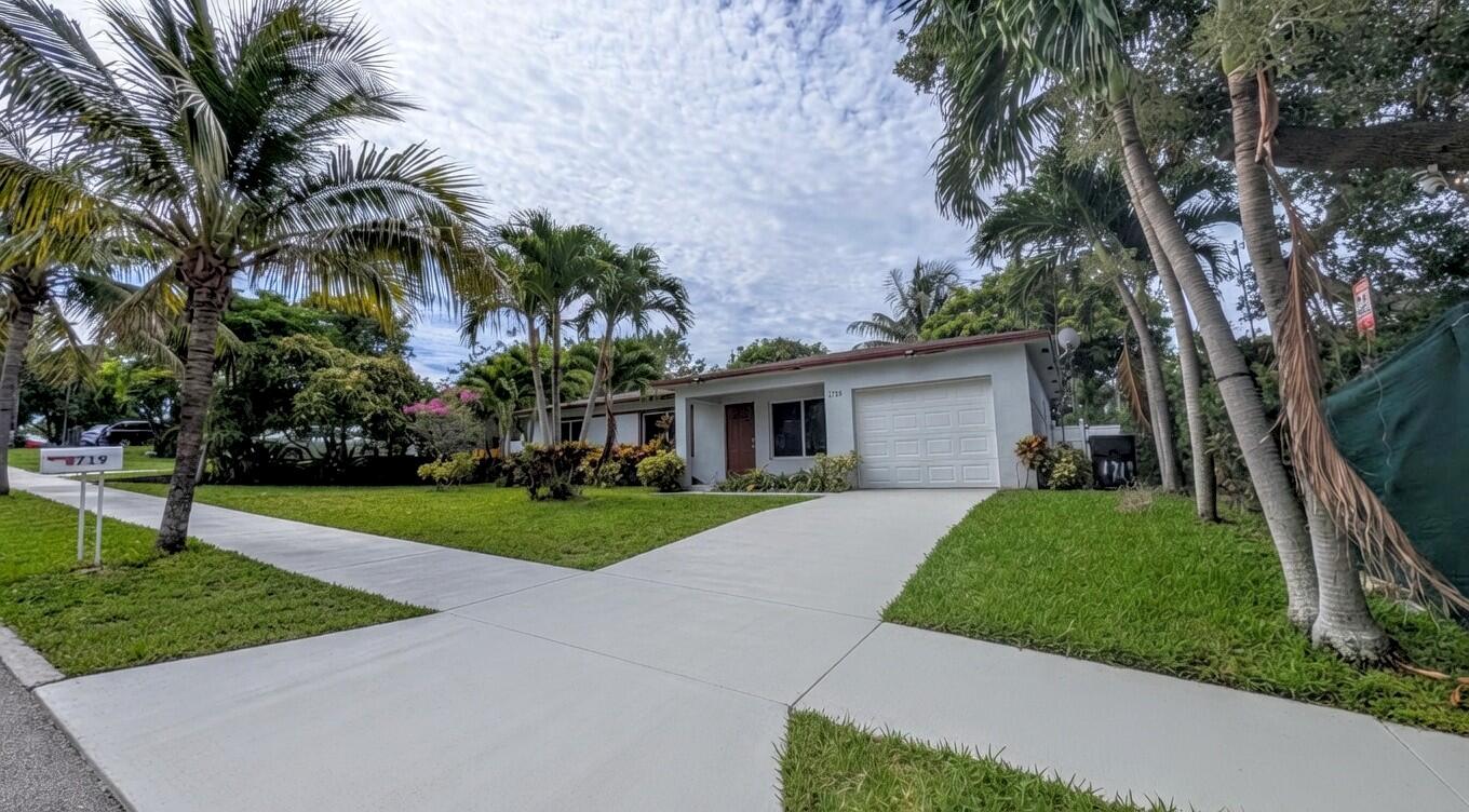 A single-story house with a white garage, a concrete driveway, and palm trees in the yard — 1719 15th Avenue N, FL 33460, FL
