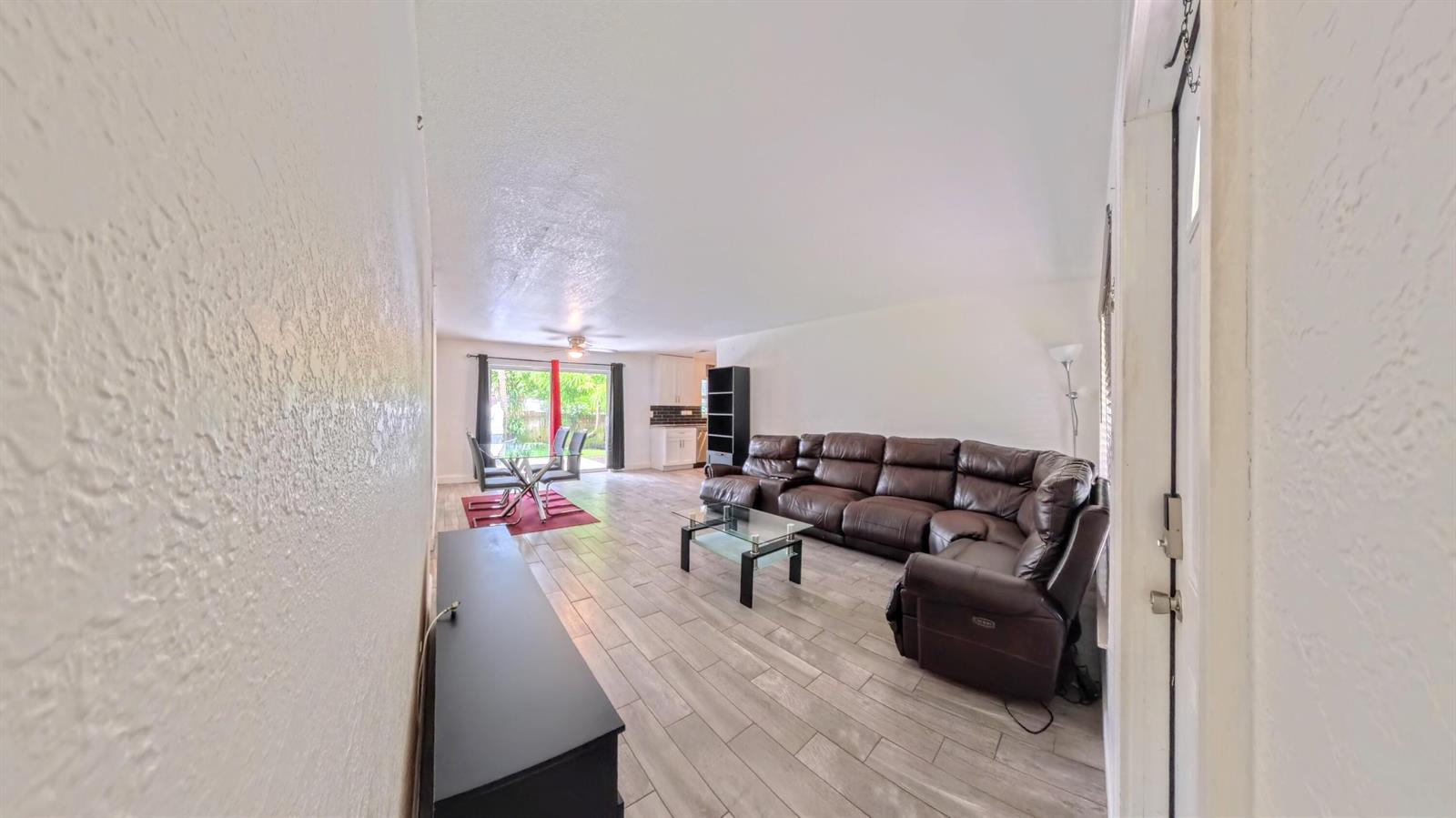 A living room with a brown sectional sofa, glass coffee table, and tile flooring — 1719 15th Avenue N, FL 33460, FL