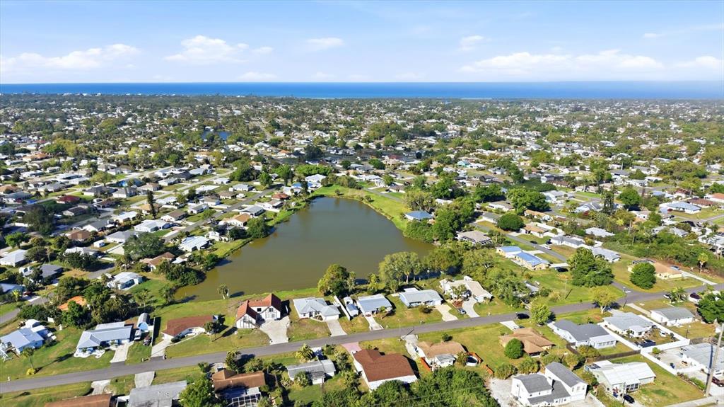 An aerial view shows a residential neighborhood surrounding a central lake near the ocean — 4452 TORTOISE ROAD, VENICE, FL