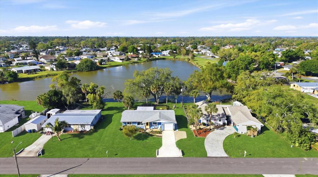 An aerial view shows three houses along a road with a lake in the background — 4452 TORTOISE ROAD, VENICE, FL