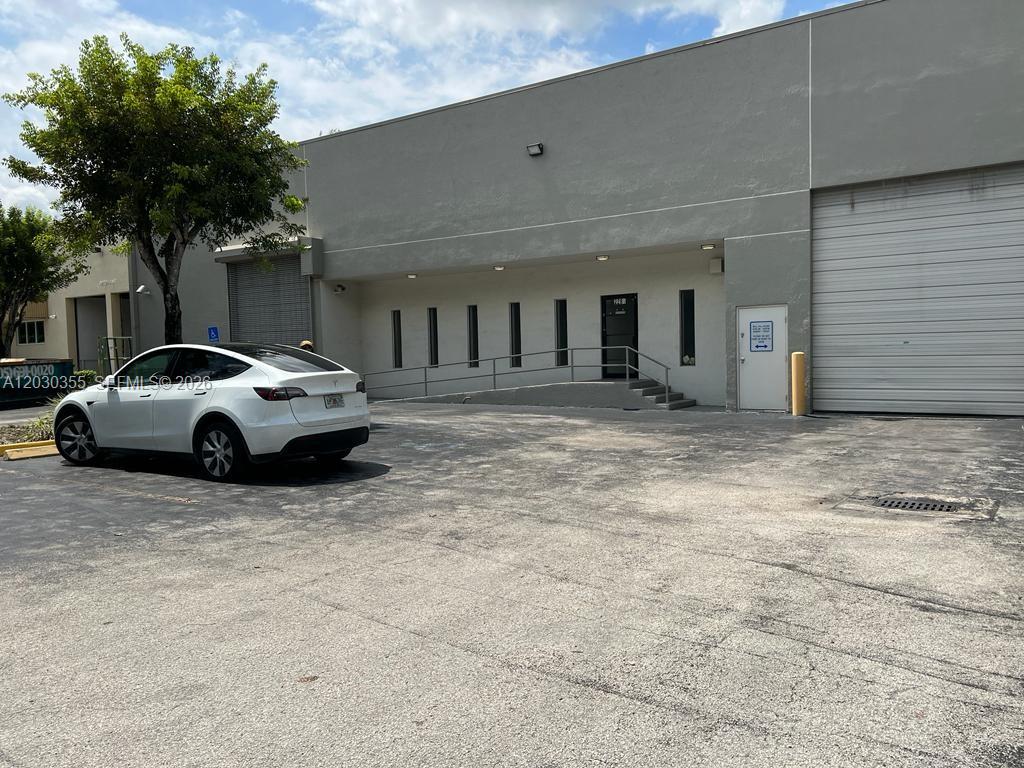 A white Tesla is parked in front of a gray industrial warehouse building — 2281 NW 95th Ave, Doral FL 33172, DORAL, FL