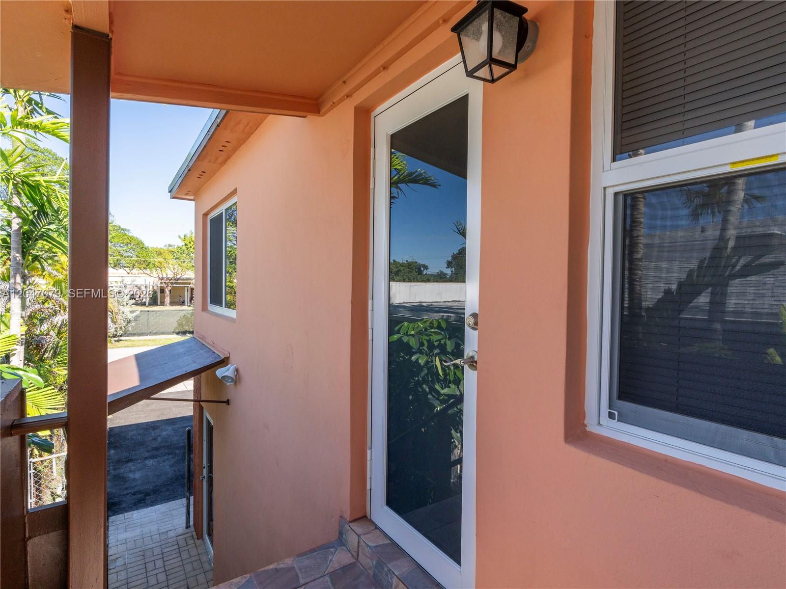 An exterior view shows a peach-colored wall with a glass door and a window — 3360 SW 6th St, Miami FL 33135, MIAMI, FL
