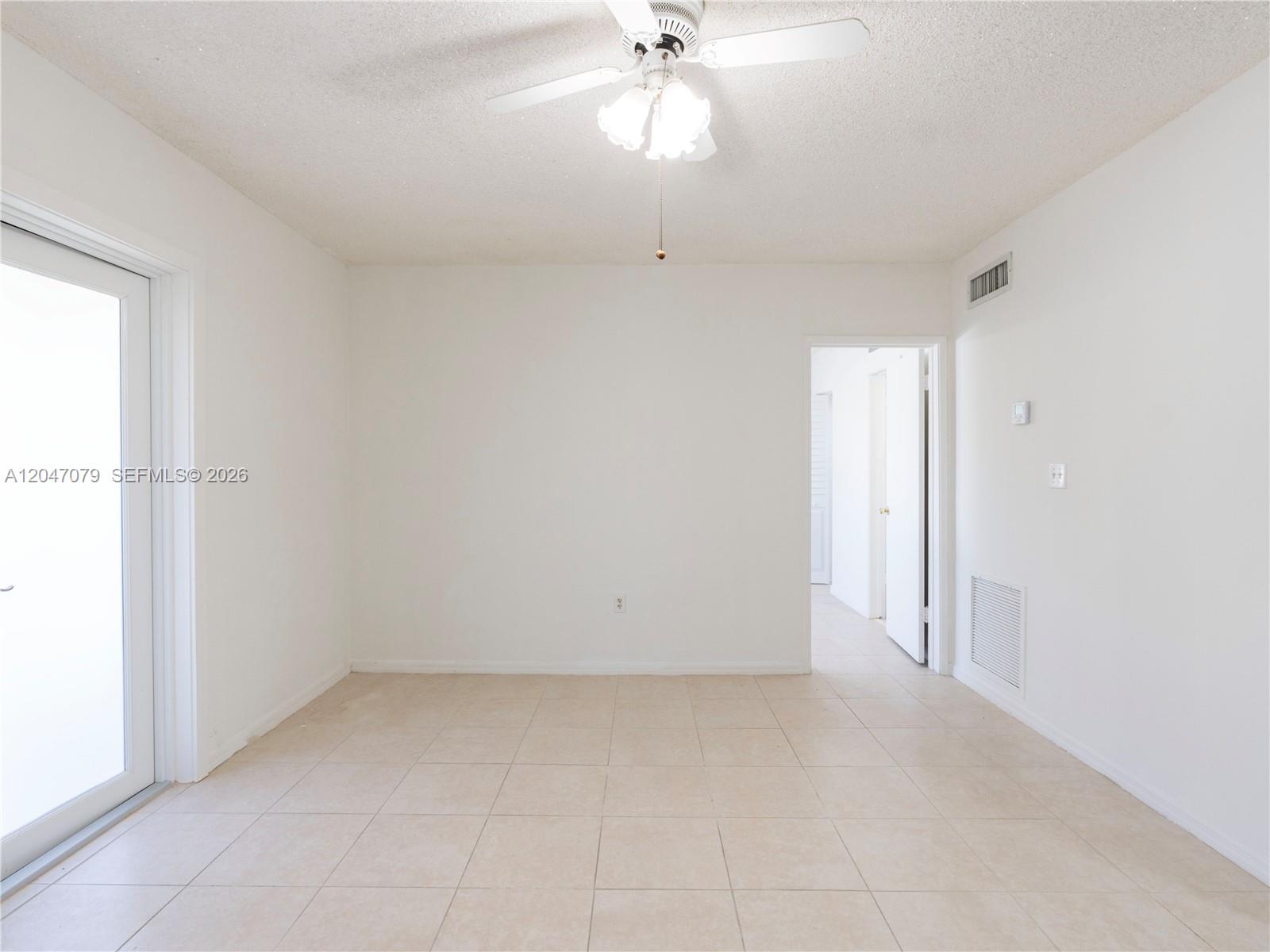 An empty room features white walls, beige tile flooring, a ceiling fan, and a sliding door — 3360 SW 6th St, Miami FL 33135, MIAMI, FL