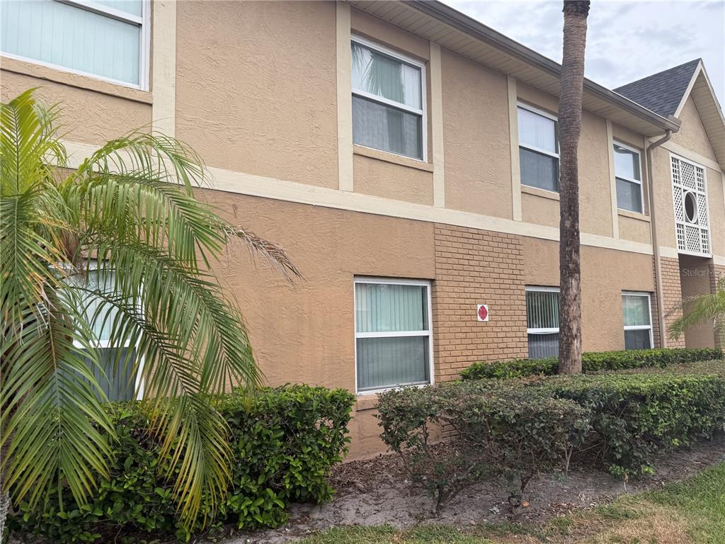 A two-story tan stucco apartment building with a brick accent wall and landscaping — 9800 TURF WAY UNIT 1, ORLANDO, FL