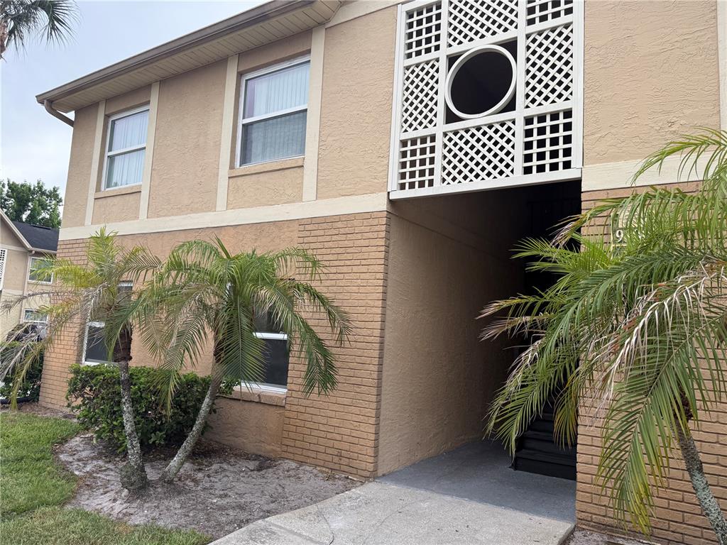 A two-story tan building features a brick lower level, palm trees, and a lattice screen — 9800 TURF WAY UNIT 1, ORLANDO, FL