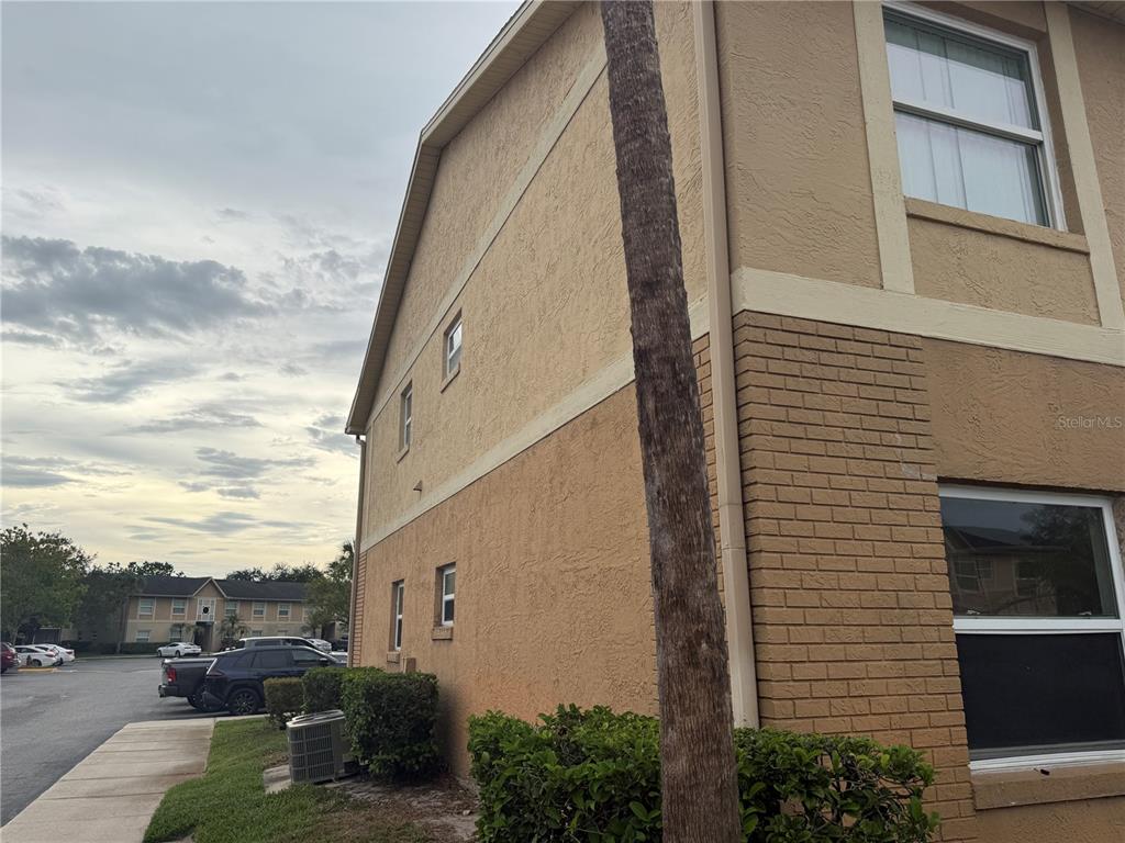 A side view of a tan stucco and brick apartment building with a palm tree — 9800 TURF WAY UNIT 1, ORLANDO, FL