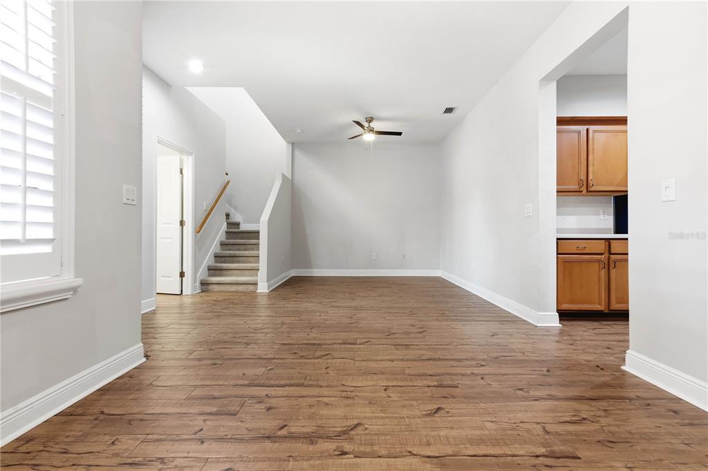 An empty room with wood-look flooring, a ceiling fan, and stairs leading to an upper level — 14606 BOURNEMOUTH ROAD, TAMPA, FL