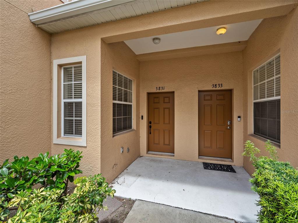 An exterior view of a covered entryway with two brown doors numbered 3831 and 3833 — 3831 PARKRIDGE CIRCLE UNIT 1-104, SARASOTA, FL