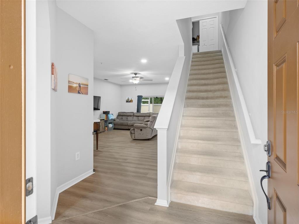 An entryway leads to a living room with wood-look flooring and a carpeted staircase — 3831 PARKRIDGE CIRCLE UNIT 1-104, SARASOTA, FL
