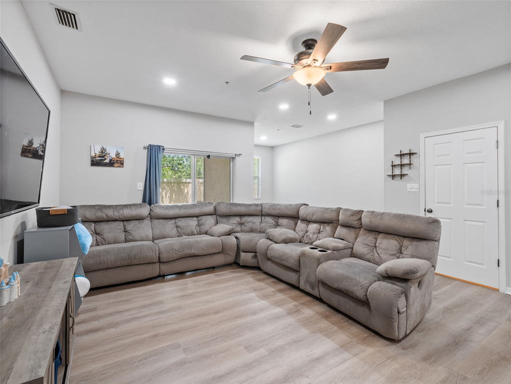 A living room features a large gray sectional sofa, wood-look flooring, and a ceiling fan — 3831 PARKRIDGE CIRCLE UNIT 1-104, SARASOTA, FL