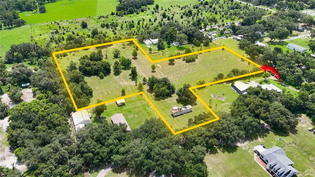 An aerial view shows a large, grassy rural property outlined in yellow with several buildings — 2452 WELCOME ROAD, LITHIA, FL