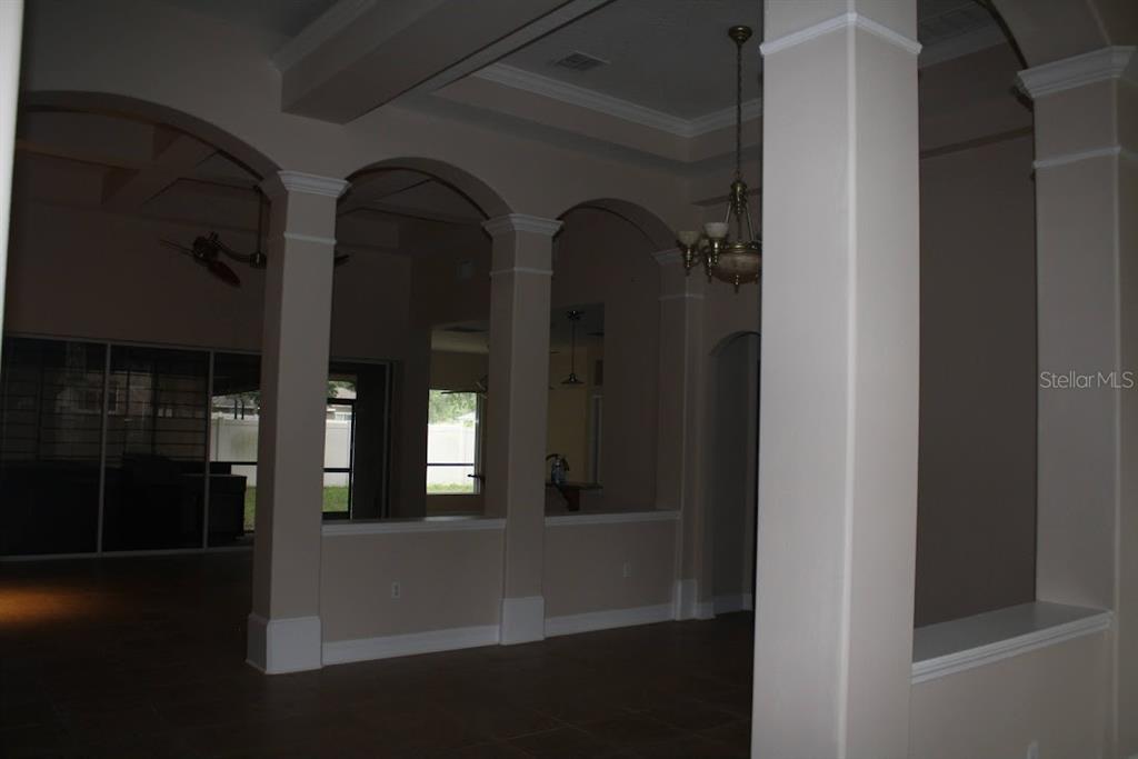 An interior view of a living area featuring arched openings, columns, and tile flooring — 2461 WOODBARK STREET, APOPKA, FL