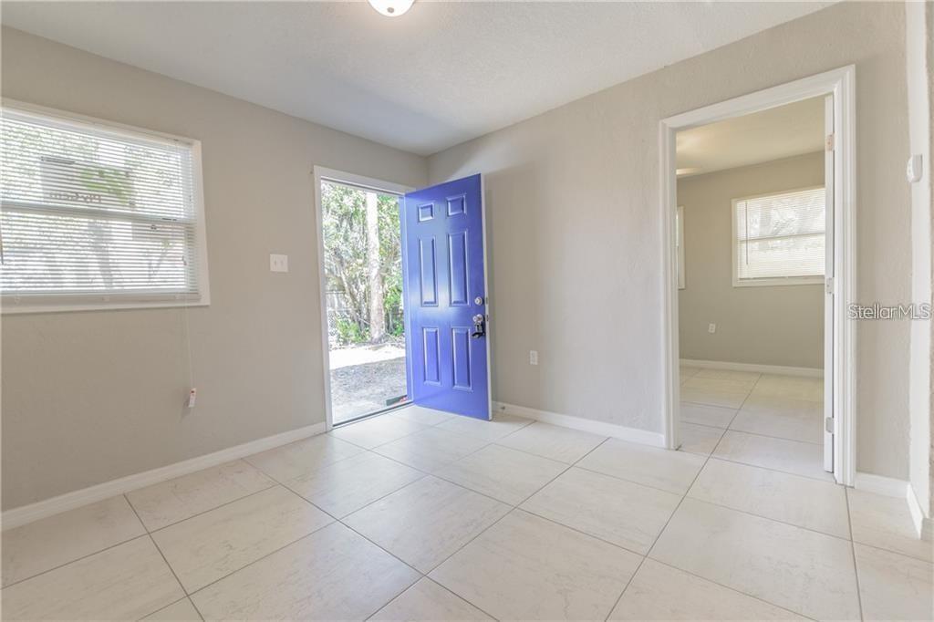 A room with light-colored tile flooring, beige walls, a blue front door, and a doorway — 5106 W RICHARDSON AVENUE UNIT B, TAMPA, FL