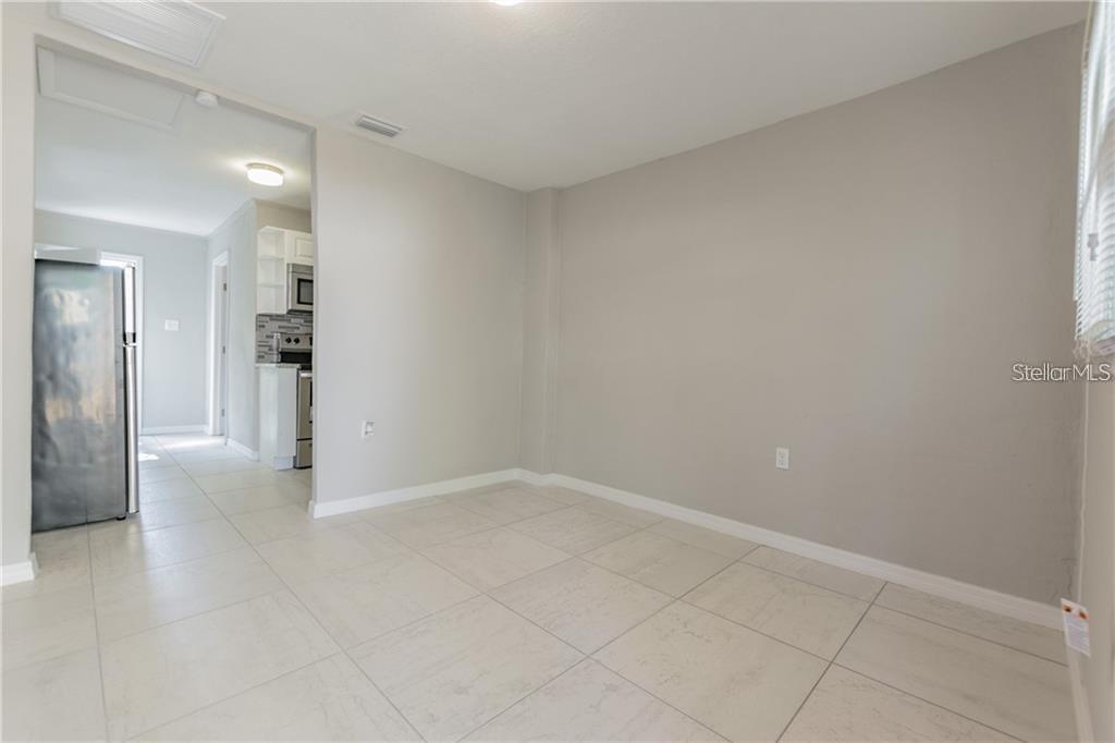 A room with light-colored tile flooring and gray walls leads into a kitchen area — 5106 W RICHARDSON AVENUE UNIT B, TAMPA, FL