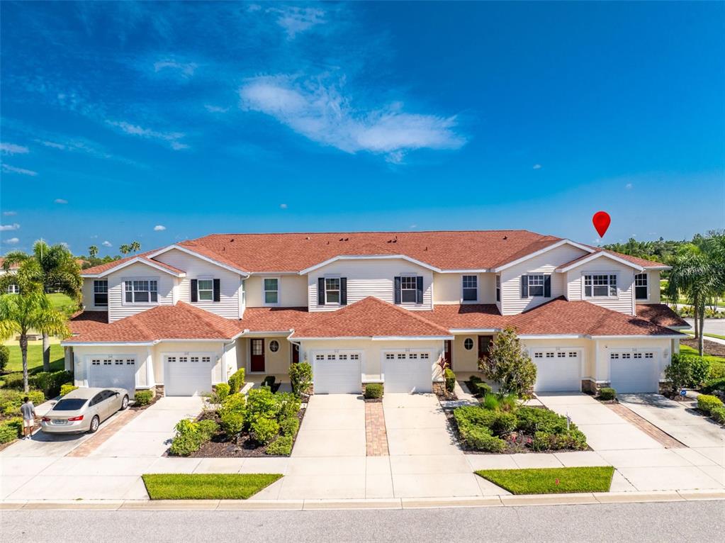 An exterior view of a multi-unit townhouse complex with attached garages and a red roof — 1158 JONAH DR, NORTH PORT, FL