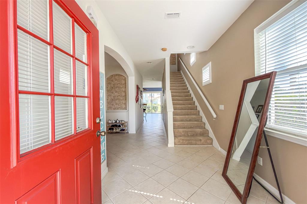 An entryway features a red front door, tiled floors, a staircase, and a floor mirror — 1158 JONAH DR, NORTH PORT, FL
