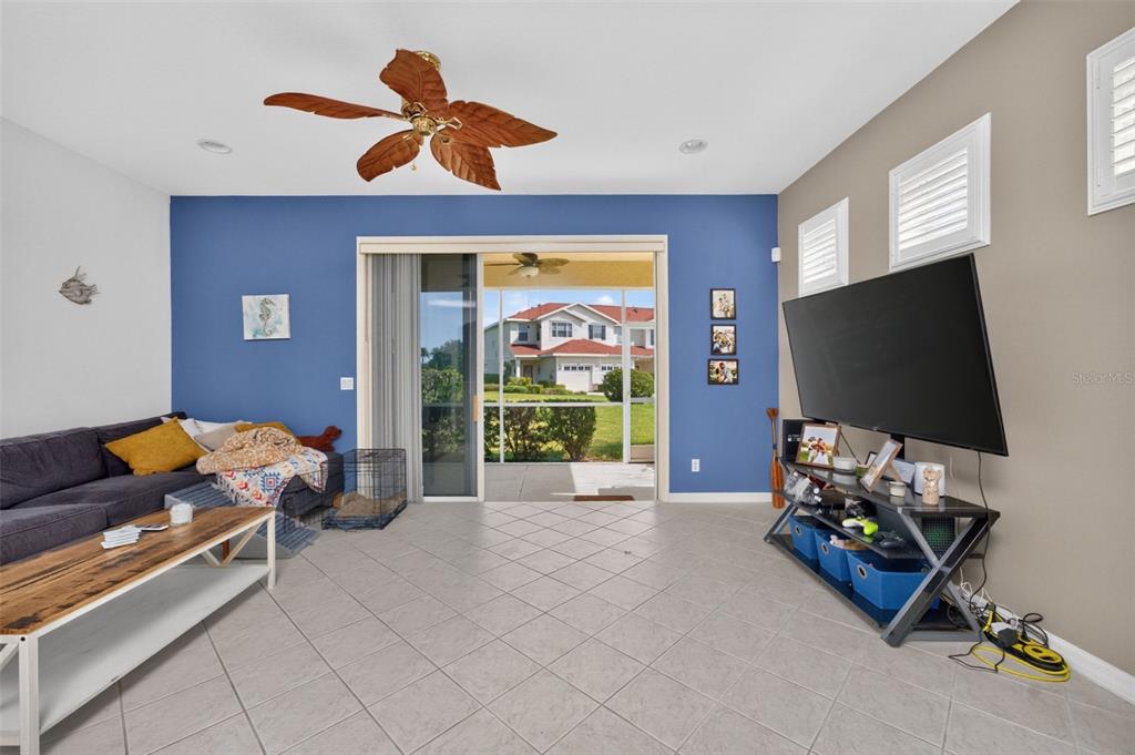 A living room with a blue accent wall, tile flooring, and a sliding glass door — 1158 JONAH DR, NORTH PORT, FL