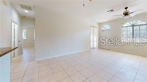 A bright, tiled living room features a ceiling fan and a large arched window — 1558 CUMIN DRIVE, POINCIANA, FL