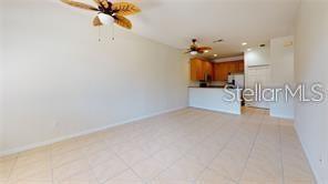 An open-concept living area features light tile flooring, two ceiling fans, and a kitchen — 1558 CUMIN DRIVE, POINCIANA, FL
