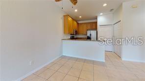 A kitchen with wood cabinets and tile flooring overlooks an open dining area — 1558 CUMIN DRIVE, POINCIANA, FL