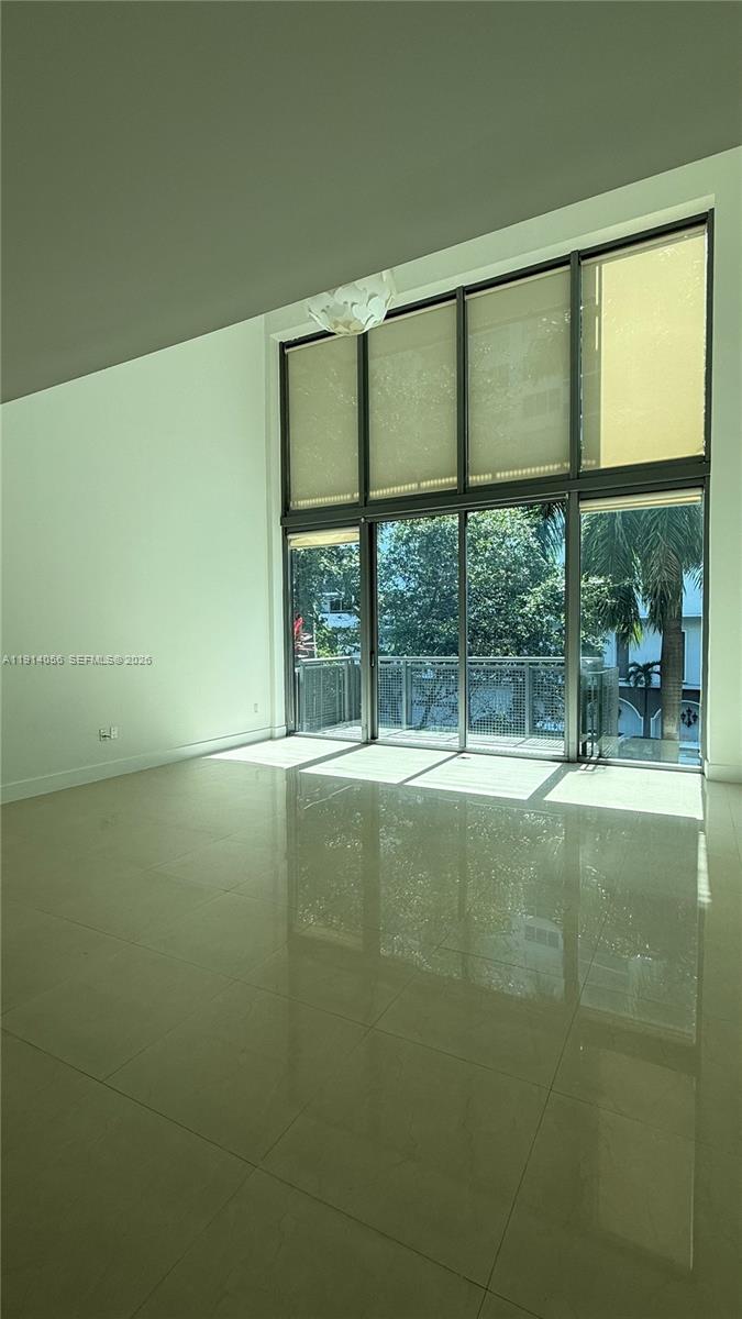 A bright living room features floor-to-ceiling windows, light tile flooring, and a balcony view — 6000 Collins Ave # 305, Miami Beach FL 33140, MIAMI BEACH, FL