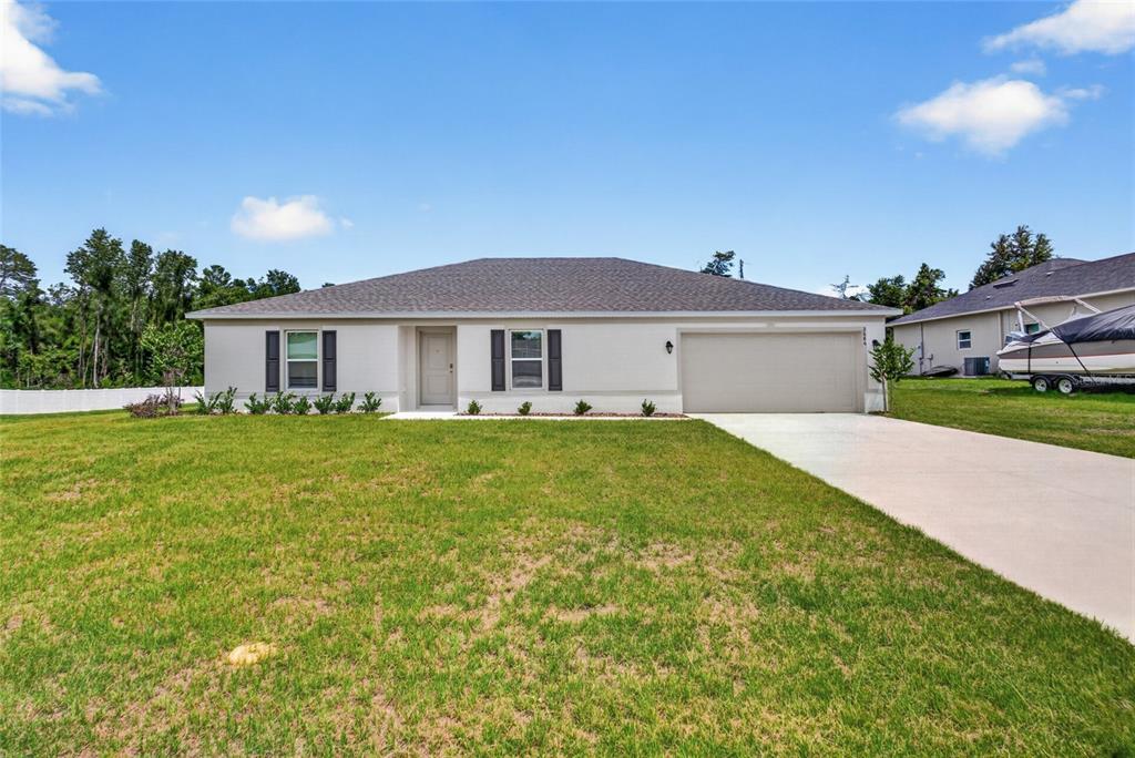 A single-story house with a light-colored exterior, a two-car garage, and a large front lawn — 2686 SW 161ST LOOP, OCALA, FL